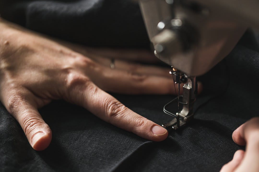 Using a sewing machine to stitch charcoal gray wool fabric